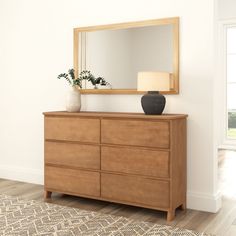 a wooden dresser with a mirror and vase on top