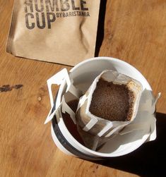 a brownie sitting in a white bowl on top of a wooden table next to a bag