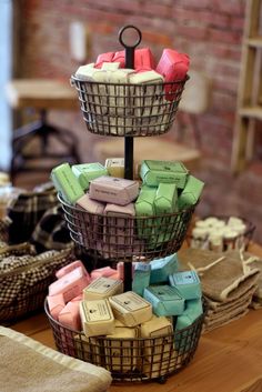 three tiered baskets filled with soaps on top of a wooden table next to other items