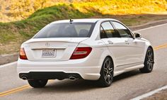 a white mercedes c - class driving down the road