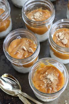 there are many desserts in glass jars with spoons next to them on the table