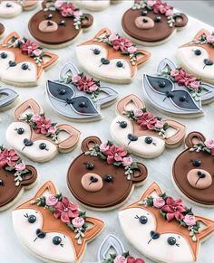 decorated cookies are arranged in the shape of animals and flowers on a white tablecloth