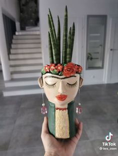 a woman's head with flowers and plants on it is held up in front of the camera