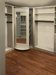 an empty walk - in closet with white walls and wooden flooring, along with several open shelving units