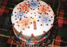 a birthday cake decorated with fireworks and beads on a plaid tablecloth covered table cloth