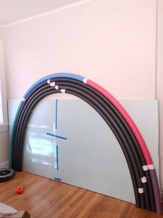 an arch made out of different colored hoses sitting on top of a hard wood floor