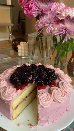 a cake with pink frosting and blackberries on top is sitting on a plate