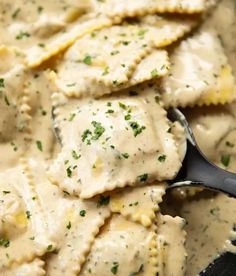 a spoon full of ravioli with cream sauce and parmesan cheese on top