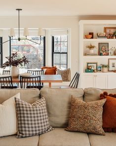 a living room filled with furniture and lots of windows next to a dining room table