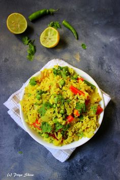 a white bowl filled with rice and vegetables next to lime wedges on a napkin