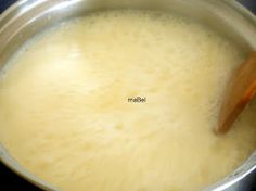 a wooden spoon is in a saucepan on the stove top, with melted cheese