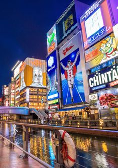 the city is lit up at night and has many billboards on both sides of it