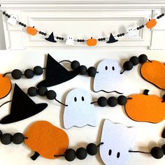 halloween decorations made out of felt with black, white and orange accents on a fireplace mantel