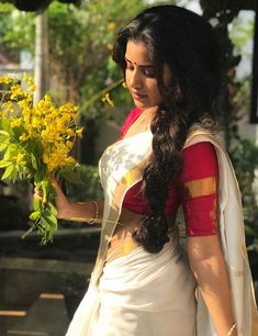 a woman in a white sari holding yellow flowers