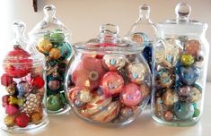 three glass jars filled with ornaments on top of a table