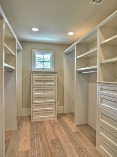 an image of a walk in closet with white shelves and drawers on the bottom shelf