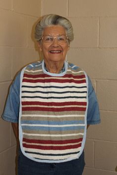 an older woman wearing glasses and a striped sweater standing in front of a brick wall