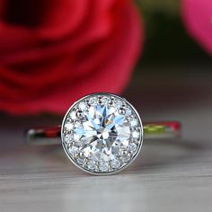 a diamond ring sitting on top of a table next to a red rose and pink flowers