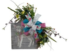 a small lamb in a wooden box decorated with flowers and ribbons, tied to it's side