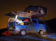 an old van parked on the side of a road at night with its roof open