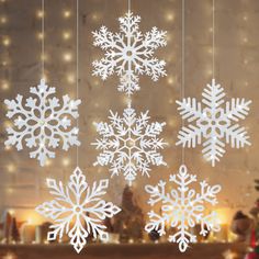 white snowflakes hanging from strings in front of a christmas tree