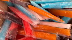 many different colored candies are in plastic wrappers on the table and one is orange, blue, and pink