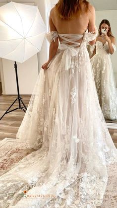 a woman in a wedding dress looking at herself in the mirror with an umbrella behind her