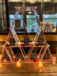 a pyramid shaped display with candles and cards on it, in front of a window