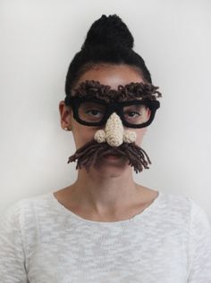 a woman with glasses and a fake moustache on her face is shown in front of a white wall