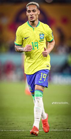 the soccer player is running on the field in yellow and blue uniforms with green socks