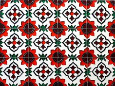 an artistic tile design with red flowers and green leaves