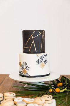 a white and black cake sitting on top of a wooden table next to oranges