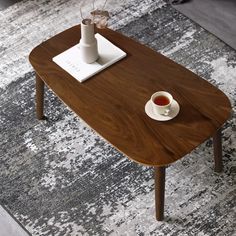 a wooden table with a white vase on it and a gray rug in the background