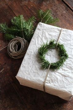 a wrapped present sitting on top of a wooden table next to a plant and twine