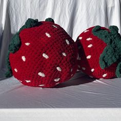 two crocheted strawberries sitting side by side on a white tablecloth background