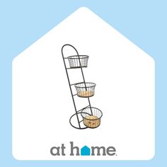 a three tiered metal basket with two baskets on it and the words at home above it