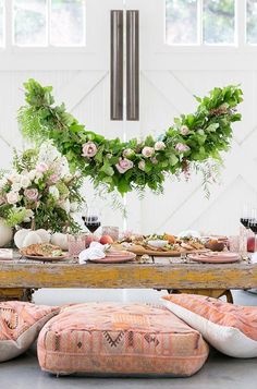 a table topped with lots of food next to a white wall and flowers on top of it