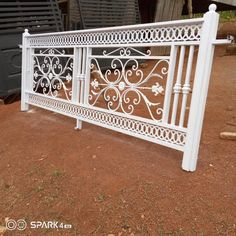 a white iron fence sitting on top of a dirt ground next to a black truck