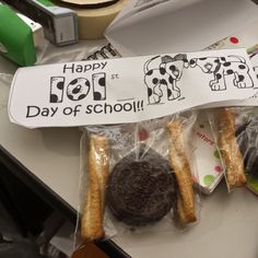 an assortment of cookies and pastries wrapped in plastic on a table with a sign that says happy hol day of school