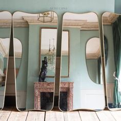 three mirrors are shown in the middle of a room with blue walls and wood flooring