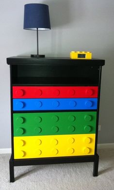 a toy chest with legos on it and a lamp in the corner next to it