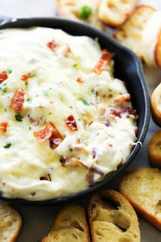 a skillet filled with cheese and bacon dip surrounded by bread slices on the side