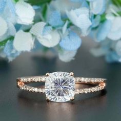 a diamond ring on top of a table next to blue flowers