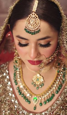 a woman in a bridal outfit with jewelry on her neck and headpieces