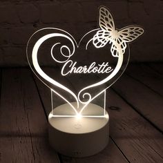 a heart shaped light with a butterfly on it that says charlotte in the center and is lit up