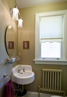 a white sink sitting under a bathroom window next to a radiator and toilet