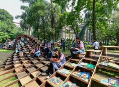 many people are sitting on wooden benches in the park