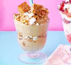 two desserts with strawberries, nuts and ice cream on a blue table next to each other