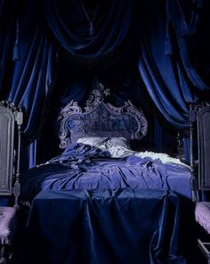 the bed is covered with blue sheets and drapes