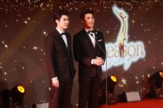 two young men in tuxedos standing on stage